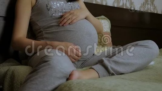 怀孕的女孩抚摸着她的胃。视频