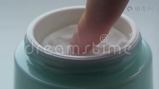 绿罐带着化妆品温和的奶油，女性手指触摸奶油近距离观看。 奶油大指法视频