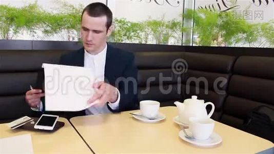 商人一边喝咖啡一边坐在咖啡馆里看文书工作视频