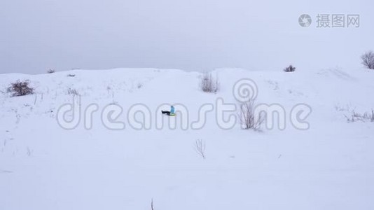 快乐的年轻女孩滑下雪滑到充气雪管上，挥动她的手。 女孩在公园里玩视频