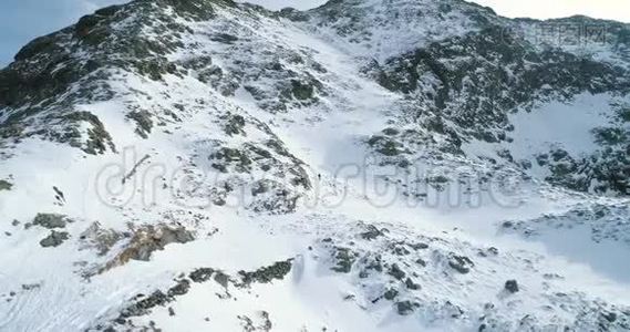 在冬天的雪山上向前飞，登山滑雪者走上登山。雪覆盖了群山视频