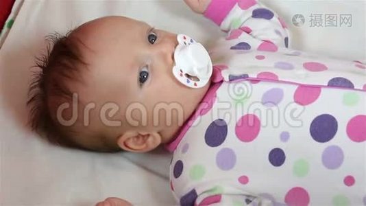 新生儿躺在床单上吸奶奶嘴。视频
