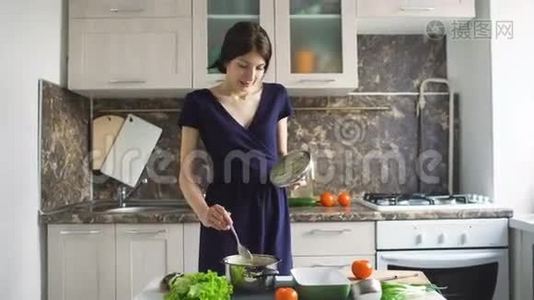有趣的女人，家庭主妇，在室内的现代厨房做饭时，用大勺子唱歌视频