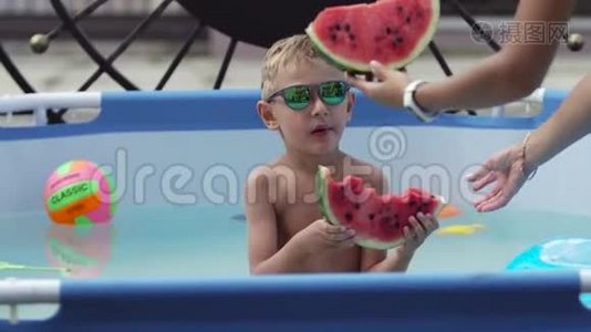 戴黑眼镜的男孩在游泳池里吃西瓜视频