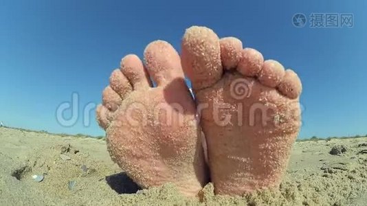 脚腿上撒着沙粒，沙粒撒在沙滩上。视频