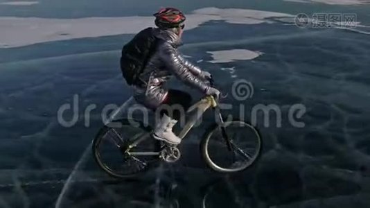 女人在冰上骑自行车。 女孩穿着银色羽绒服，自行车背包和头盔。 射击视频