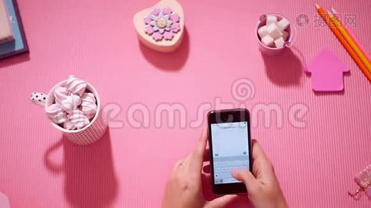 顶视图女孩用粉红色在智能手机上写短信视频