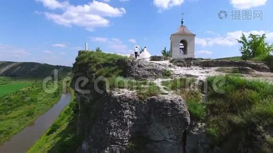在河的悬崖上散步的新婚夫妇的鸟瞰图视频