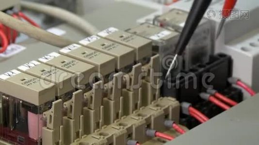 工人手检查工厂电子产品中的触点电压指示器。视频