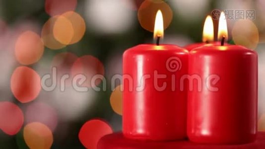三支圣诞蜡烛在模糊的圣诞树前旋转视频