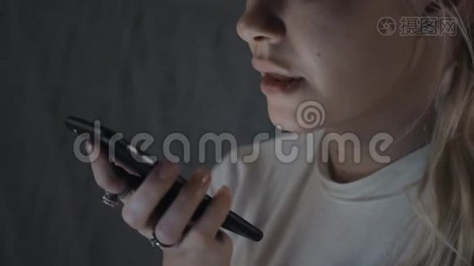 女孩使用智能手机语音识别，口述想法，语音拨号信息，晚上在家学生模特视频