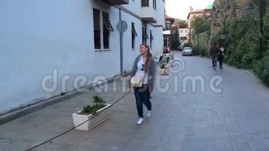 黄昏时分，一个背着包的年轻女子沿着欧洲老街散步视频
