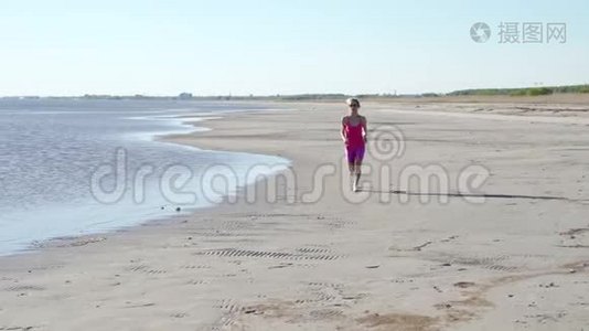 在阳光明媚的海滨背景下，独立的年轻女子运动员在海滩上跑步运动，女子跑步者短跑训练视频