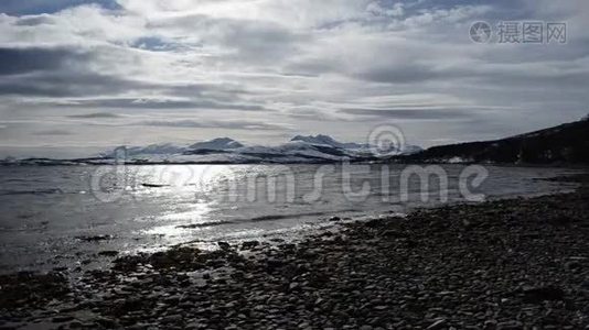 秋末，在雪山背景下，清晰的寒潮冲击着浅棕色的沙质海岸视频