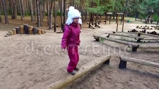 戴眼镜的女孩用木头做衣服. 小德奥夫奇卡在操场上玩。 一个多云的秋日视频