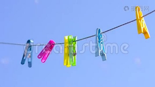 彩色衣夹在晾衣绳上，迎风蓝天。视频
