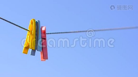 彩色衣服钉在亚麻绳上，摆动在蓝天的背景上。视频