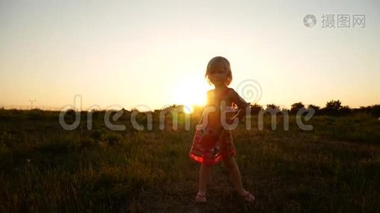 那个女孩在夕阳的光线下在田野里旋转。视频