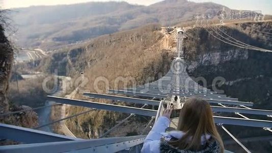 女人在峡谷上空的天空桥上拍摄自然风光视频