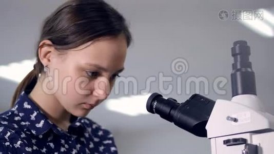 学校女生看显微镜。 特写镜头。视频