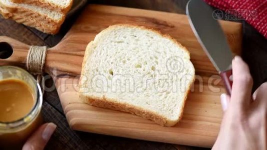 在白三明治面包上涂花生酱视频