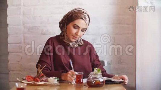 在咖啡馆里戴头巾的漂亮穆斯林女孩。视频