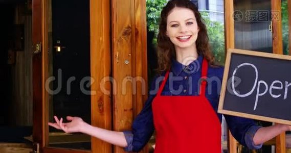 微笑的女服务员拿着开放的招牌视频