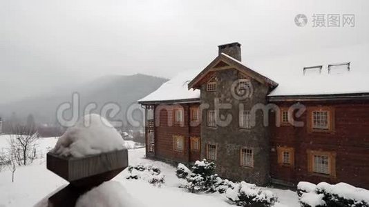 大雪时山村的木屋，背景是针叶林。落在原木上的雪视频