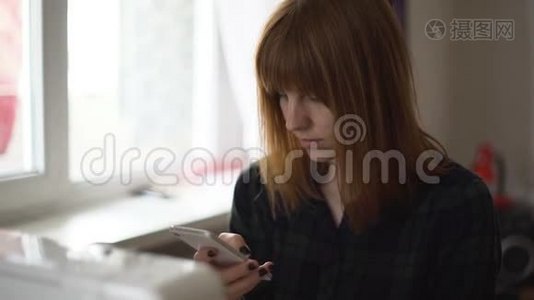 年轻漂亮的红发女郎在家里使用智能手机视频
