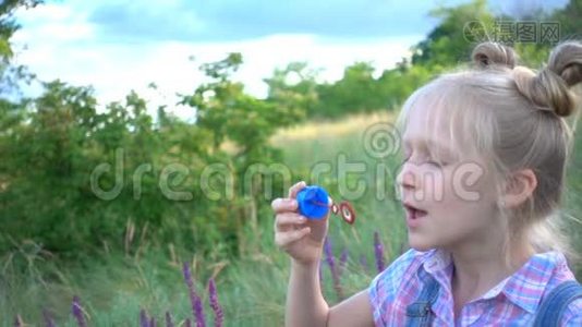 小女孩在绿色草坪上吹肥皂泡视频
