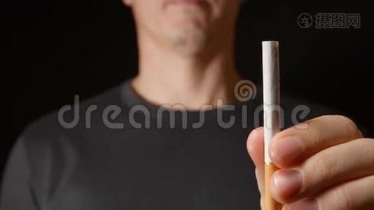 年轻人一只手拿着一支烟，然后把它折断视频