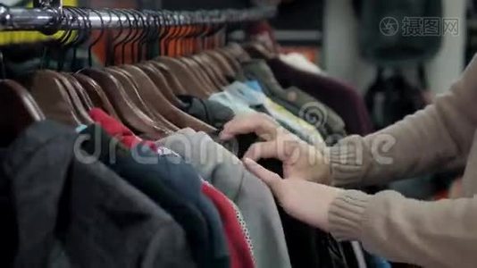 在一家零售服装店，男士毛衣和不同颜色的衬衫挂在衣架上，男士则选择店里贴身的帽衫视频