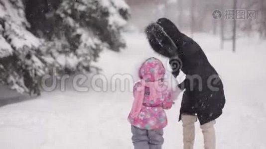 父母和孩子在雪地里玩耍。 妈妈和女儿在冬天的树林里雕刻雪。视频