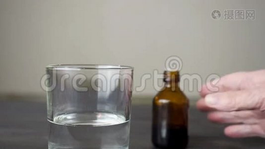 老年妇女用液体药物将药物滴入深色瓶子中的一杯水中视频