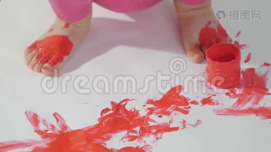一个小女孩的特写镜头，她的手沾满了红色的颜料，她的手指在一张大白纸上视频