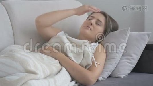 不高兴的年轻女子头痛躺在客厅的沙发上。 4K拍摄的录像视频