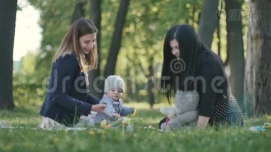 两个女人带着小男孩在绿色公园的封面上放松视频