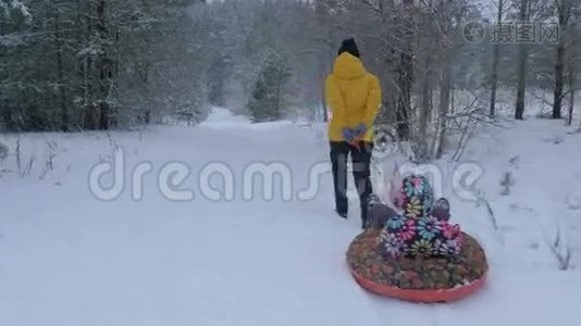 女人在冬天公园里和一个孩子拉雪橇。 Stadicam动议，4K视频