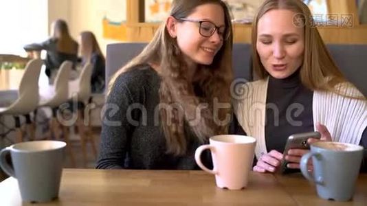 两个朋友的女人在咖啡馆里用手机交流视频