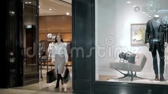 漂亮的商务女性，穿着豪华西装在购物中心漫步时，背着购物袋视频