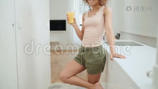 快乐混血女人在家喝橙汁。视频