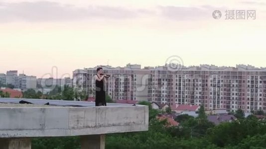 美丽的年轻女子在屋顶上拉小提琴。视频