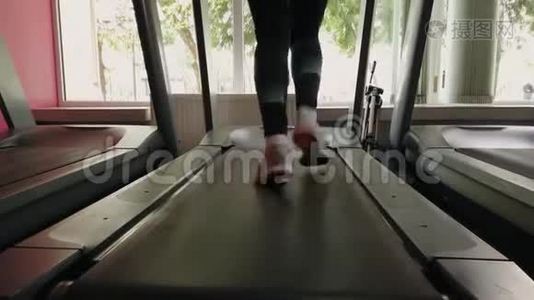 年轻女孩在运动健身房的跑步机上跑步。视频