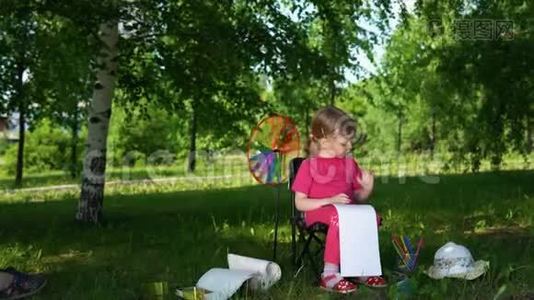 夏天在公园户外画铅笔的小女孩的肖像。视频