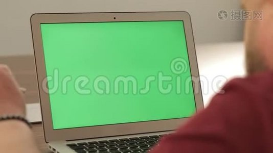 创意经理工作。 商业概念。 自信的年轻人在他的笔记本电脑上用彩色钥匙绿色屏幕视频