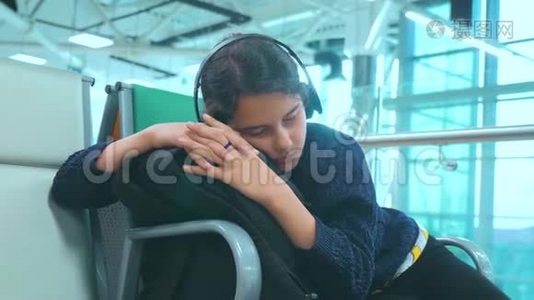 一个戴着耳机的少女，睡在机场等着飞机起飞的大门长椅上的旅行者视频