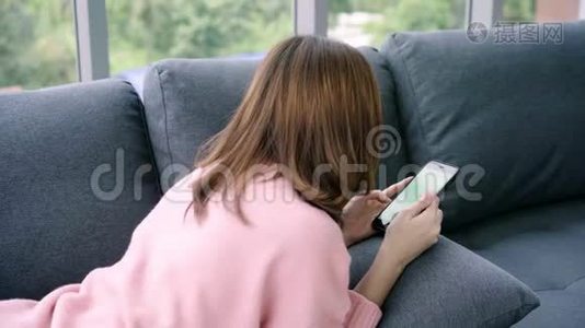 年轻的亚洲女性使用带有绿色屏幕的黑色智能手机设备。视频