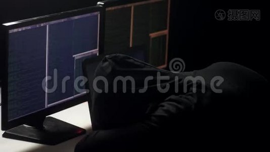 一个疲惫的黑客在黑暗的房间里的电脑上工作。 他把头放在桌子上。 黑客整晚都在工作。视频