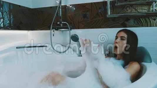快乐的女孩在浴室里洗了满是泡沫的澡。 好好享受。 在肥皂泡沫上吹气。视频