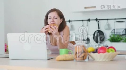 女人吃汉堡包，用笔记本电脑工作视频